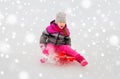 Happy little girl sliding down on sled in winter