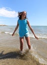 Happy little girl smiles on the shore on the beach near the sea