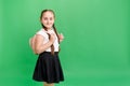 Happy little girl smiling aand holding backpack while standing in studio on green background