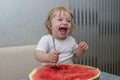 Happy little girl smiling and eating watermelon, holding a large spoon, vitamins, summer Royalty Free Stock Photo