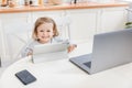 Happy little girl smiling and looking to the camera while watching cartoons. Pretty kid sitting at home while quarantine Royalty Free Stock Photo