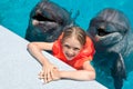 Happy Little Girl Smiling with two Dolphins in Swimming Pool Royalty Free Stock Photo