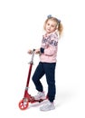 A happy little girl in sports clothes stands with a red scooter, isolated on a white background Royalty Free Stock Photo