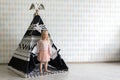 Happy little girl standing near children tent in empty playroom Royalty Free Stock Photo