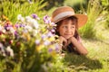 Happy little girl in a straw hat dreams while lying on the grass in the garden Royalty Free Stock Photo