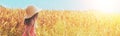 A happy little girl in a straw hat walks through a wheat field in the summer Royalty Free Stock Photo