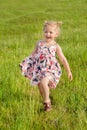 little girl in summer dress with pigtails run in a green field, light of warm rays of the sun Royalty Free Stock Photo