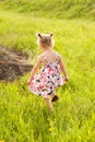 Happy little girl in summer dress with pigtails run in a green field, light of warm rays of the sun Royalty Free Stock Photo