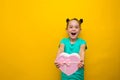 Happy little girl with tails standing isolated over yellow background holding shopping pink bag. smiles thoughtfully Royalty Free Stock Photo