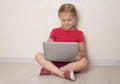 Happy little girl using laptop sitting on the floor at home. Homeschooling e-learning or distance education concept Royalty Free Stock Photo