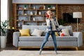 Happy little girl wearing red headphones dancing and singing, jumping on a floor. Cute child enjoy listening favorite Royalty Free Stock Photo