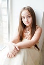 Happy little girl a on white background sitting on the window sill Royalty Free Stock Photo