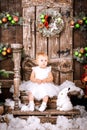 Happy little girl in white dress sitting in the Christmas wooden brown decorated room interior Royalty Free Stock Photo