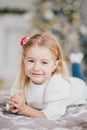 Happy little girl in a white sweater and blue jeans posing near christmas tree Royalty Free Stock Photo