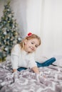 Happy little girl in a white sweater and blue jeans posing near christmas tree Royalty Free Stock Photo