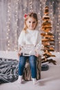 Happy little girl in a white sweater and blue jeans posing near christmas tree Royalty Free Stock Photo