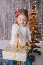 Happy little girl in a white sweater and blue jeans posing near christmas tree Royalty Free Stock Photo