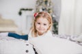 Happy little girl in a white sweater and blue jeans posing near christmas tree Royalty Free Stock Photo