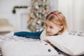 Happy little girl in a white sweater and blue jeans posing near christmas tree Royalty Free Stock Photo