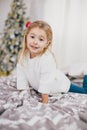 Happy little girl in a white sweater and blue jeans posing near christmas tree Royalty Free Stock Photo