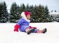 happy little girl in winter clothes sits on snow