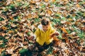 Happy little girl in yellow jacket playing with autumn leaves in park. Child in outdoor fun in fall season. Smiling cute toddler Royalty Free Stock Photo