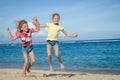 Happy little girls jumping on beach Royalty Free Stock Photo