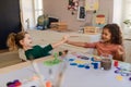 Happy little girls painting picture during creative art and craft class at school.