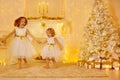 Happy Little Girls Playing Next to Christmas Tree with Gifts in White Home Room Interior with Fireplace Candles and Golden Xmas Royalty Free Stock Photo