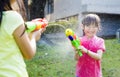 Happy little girls playing water guns in the park