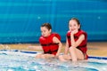 Happy little girls in a red vest swimming in the pool of the water park. Child learns to swim. teaching a child to swim