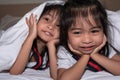 Happy little girls twins sister in bed under the blanket having fun, smiling and wacky Royalty Free Stock Photo