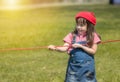 Happy little gril playing rope tug of war in park