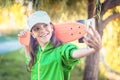 Happy little hipster girl taking selfie with cell phone while holding skateboard Royalty Free Stock Photo