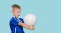 Happy little kid in a blue shirt with a ball for volleyball. Physical, sport