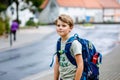 Happy little kid boy with backpack or satchel. Schoolkid on the way to middle or high school. Healthy adorable child