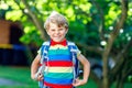 Happy little kid boy with glasses and backpack or satchel on his first day to school or nursery. Child outdoors on warm Royalty Free Stock Photo