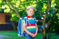 Happy little kid boy in colorful shirt and backpack or satchel on his first day to school or nursery. Child outdoors on Royalty Free Stock Photo