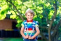 Happy little kid boy in colorful shirt and backpack or satchel on his first day to school or nursery. Child outdoors on Royalty Free Stock Photo