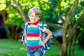 Happy little kid boy in colorful shirt and backpack or satchel on his first day to school or nursery. Child outdoors on Royalty Free Stock Photo