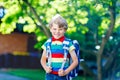 Happy little kid boy in colorful shirt and backpack or satchel on his first day to school or nursery. Child outdoors on Royalty Free Stock Photo