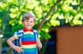 Happy little kid boy in colorful shirt and backpack or satchel on his first day to school or nursery. Child outdoors on Royalty Free Stock Photo