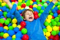 Happy little kid boy playing at colorful plastic balls playground high view. Funny child having fun indoors. Royalty Free Stock Photo