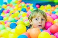 Happy little kid boy playing at colorful plastic balls playground high view. Funny child having fun indoors Royalty Free Stock Photo