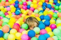 Happy little kid boy playing at colorful plastic balls playground high view. Funny child having fun indoors Royalty Free Stock Photo