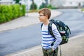 Happy little kid boy with satchel and eyeglasses. Schoolkid wearing glasses on the way to middle or high school. Excited