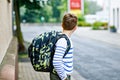 Happy little kid boy with satchel and eyeglasses. Schoolkid wearing glasses on the way to middle or high school. Excited