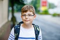 Happy little kid boy with satchel and eyeglasses. Schoolkid wearing glasses on the way to middle or high school. Excited