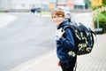 Happy little kid boy with satchel and eyeglasses. Schoolkid wearing glasses on the way to middle or high school. Excited