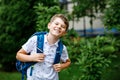 Happy little kid boy with satchel, walking. Schoolkid on the way to middle or high school. Excited child outdoors on